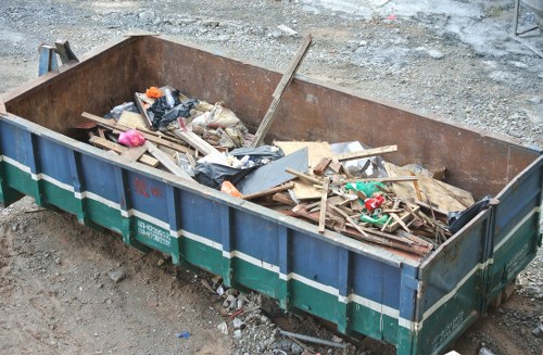 Construction site with builders managing waste clearance in Bow